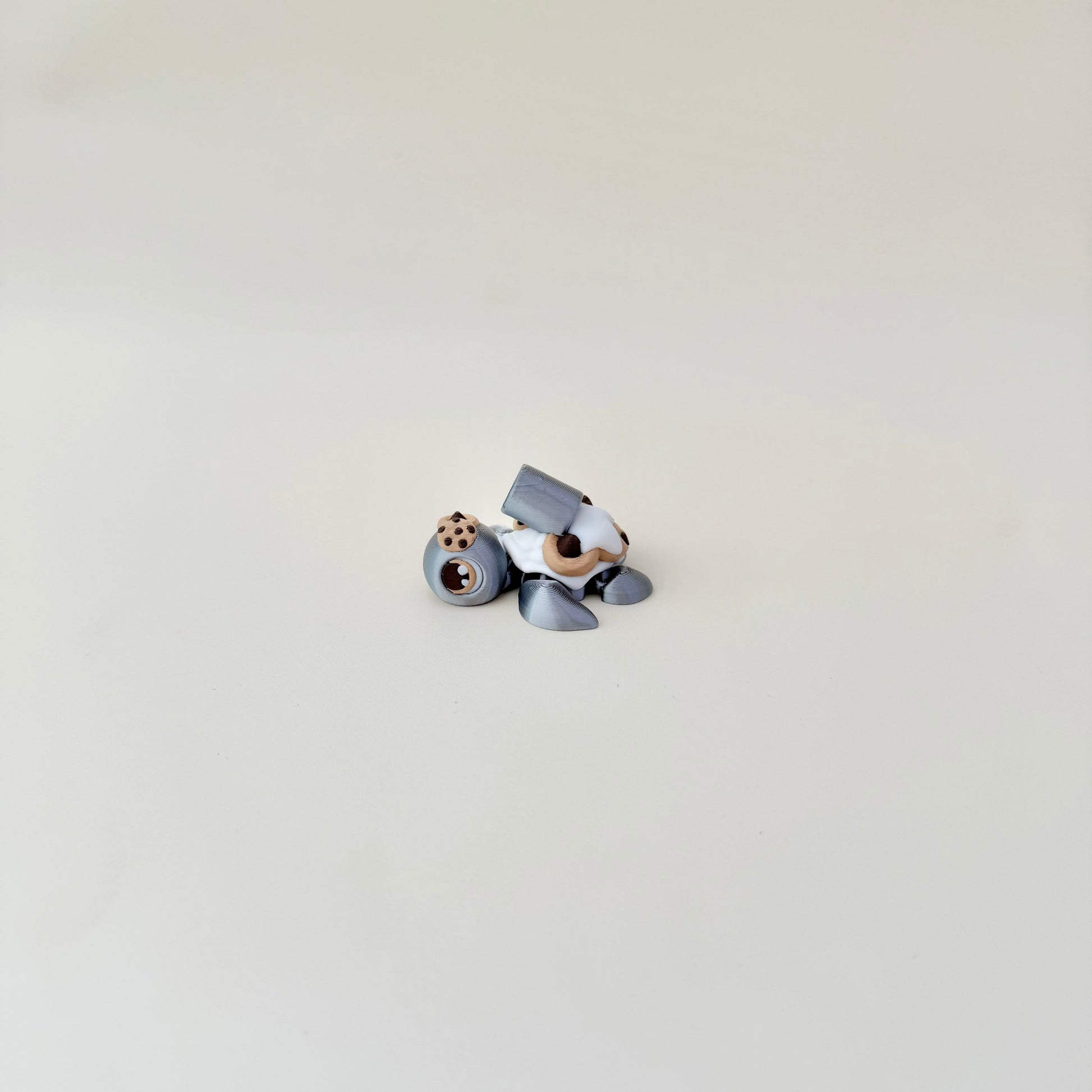 Compact 5 cm articulated turtle in metallic silver with textured cookie back; calming handheld fidget.
