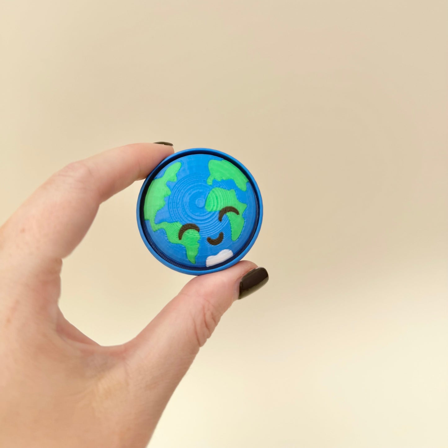 Handheld round fidget with simple press movement, textured details for sensory input.
