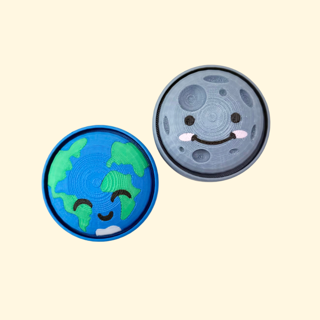 Round space-themed clicker fidget, approx 5 cm, smooth/raised details, optional quiet press.
