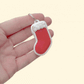 Holiday stocking-shaped clicker, smooth press surface with textured cuff for contrast; pocket-size stim tool for neurodivergent users.

