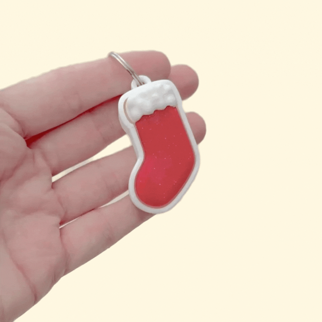 Holiday stocking-shaped clicker, smooth press surface with textured cuff for contrast; pocket-size stim tool for neurodivergent users.
