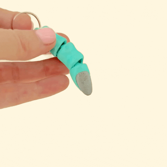 Green finger with black nail on metal keyring
