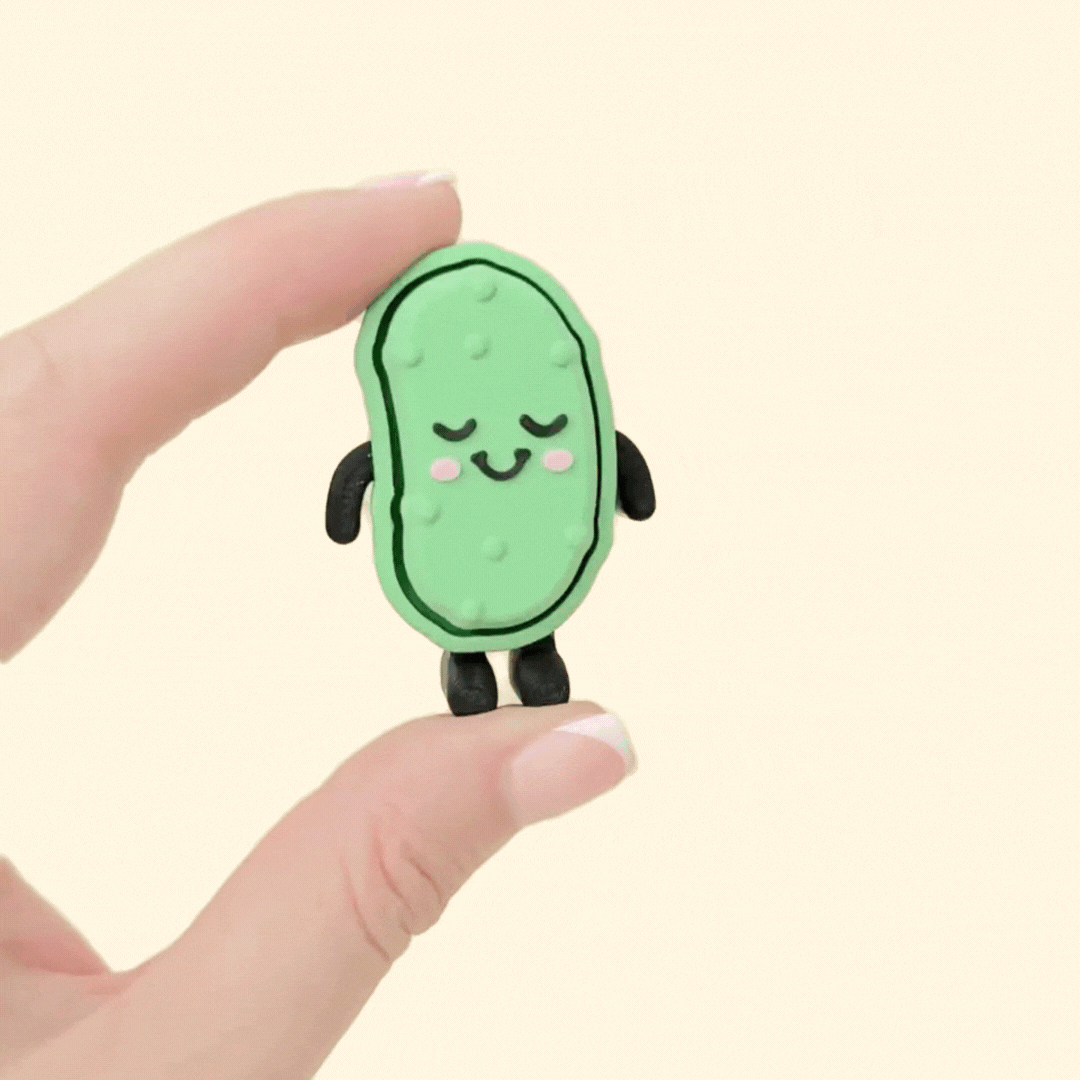 Blushing pickle fidget toy that stands upright and features different textures for sensory input.