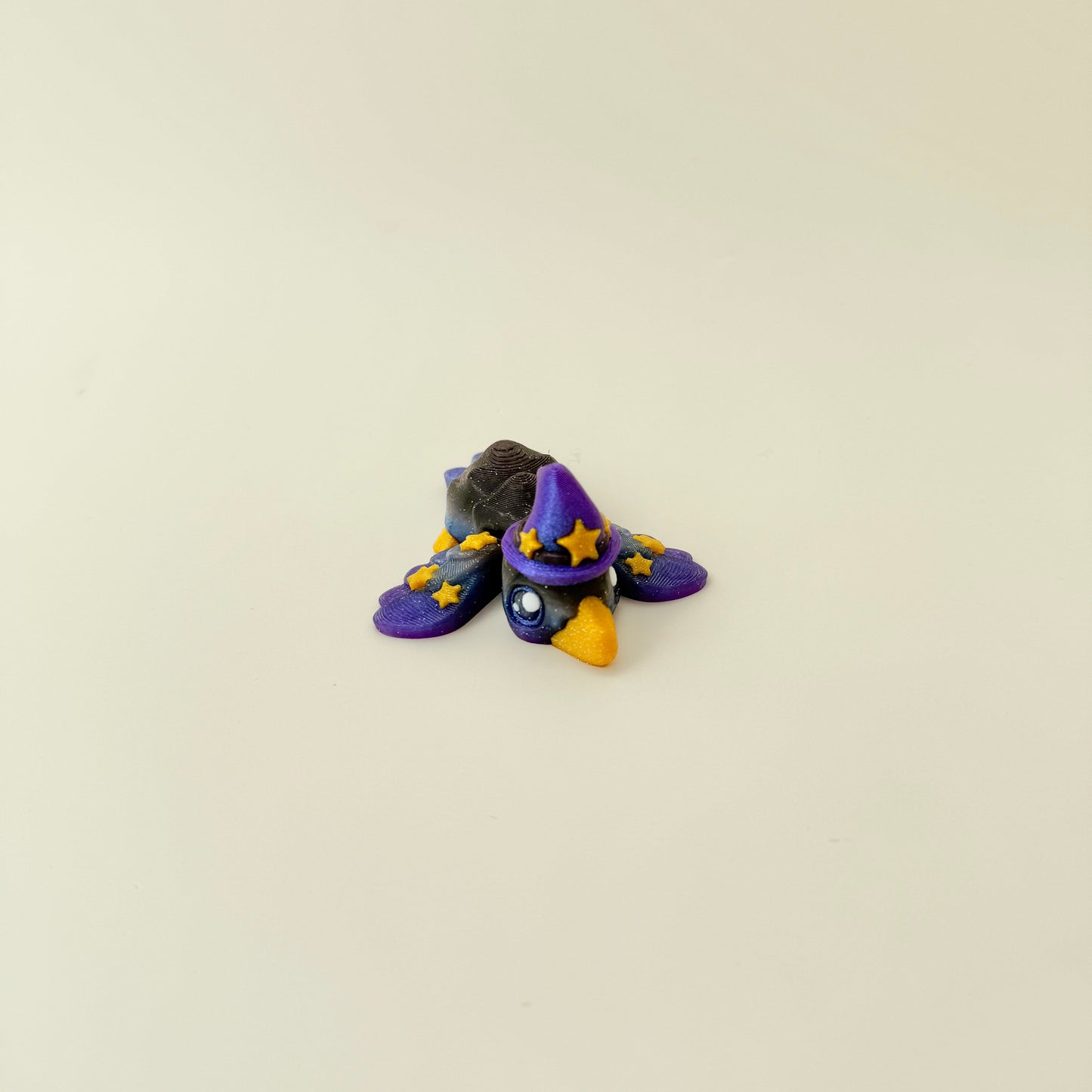 Black, purple and blue gradient bird with raised gold star details.
