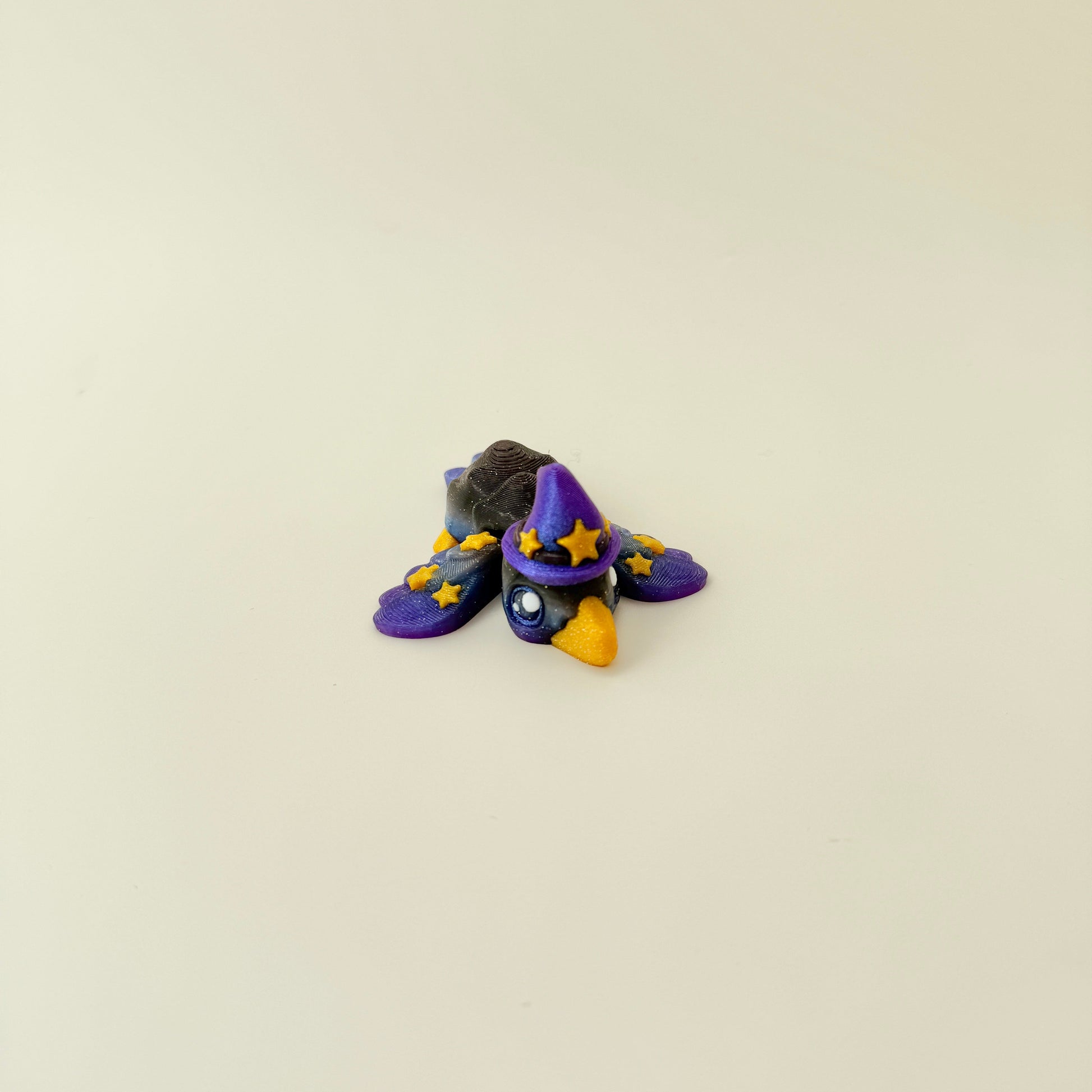 Black, purple and blue gradient bird with raised gold star details.
