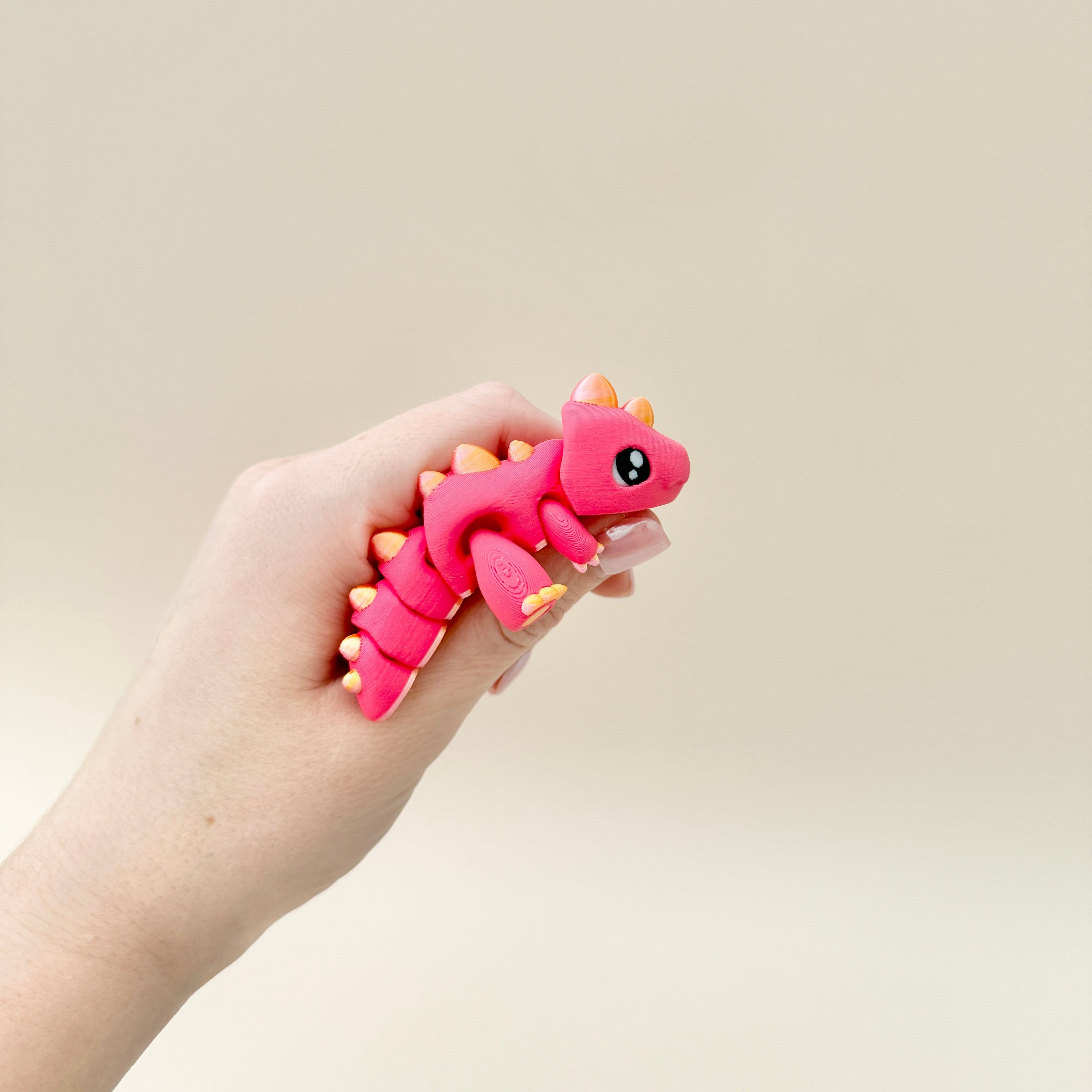 Cute red dinosaur toy with golden spikes and claws, fully articulated for standing, lying flat, and sensory play.
