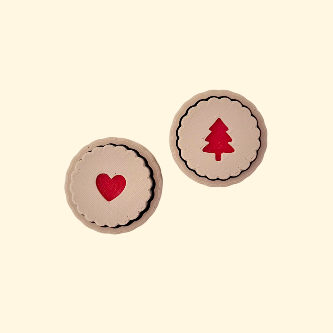 Small biscuit-shaped fidget with textured edge and red centre, ~3 cm, press to click, optional quiet version, two designs for sensory regulation.