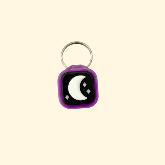 Keychain with a black square design featuring a white crescent moon on a beige background