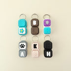Set of colorful keychains with letter and symbol designs on a beige background