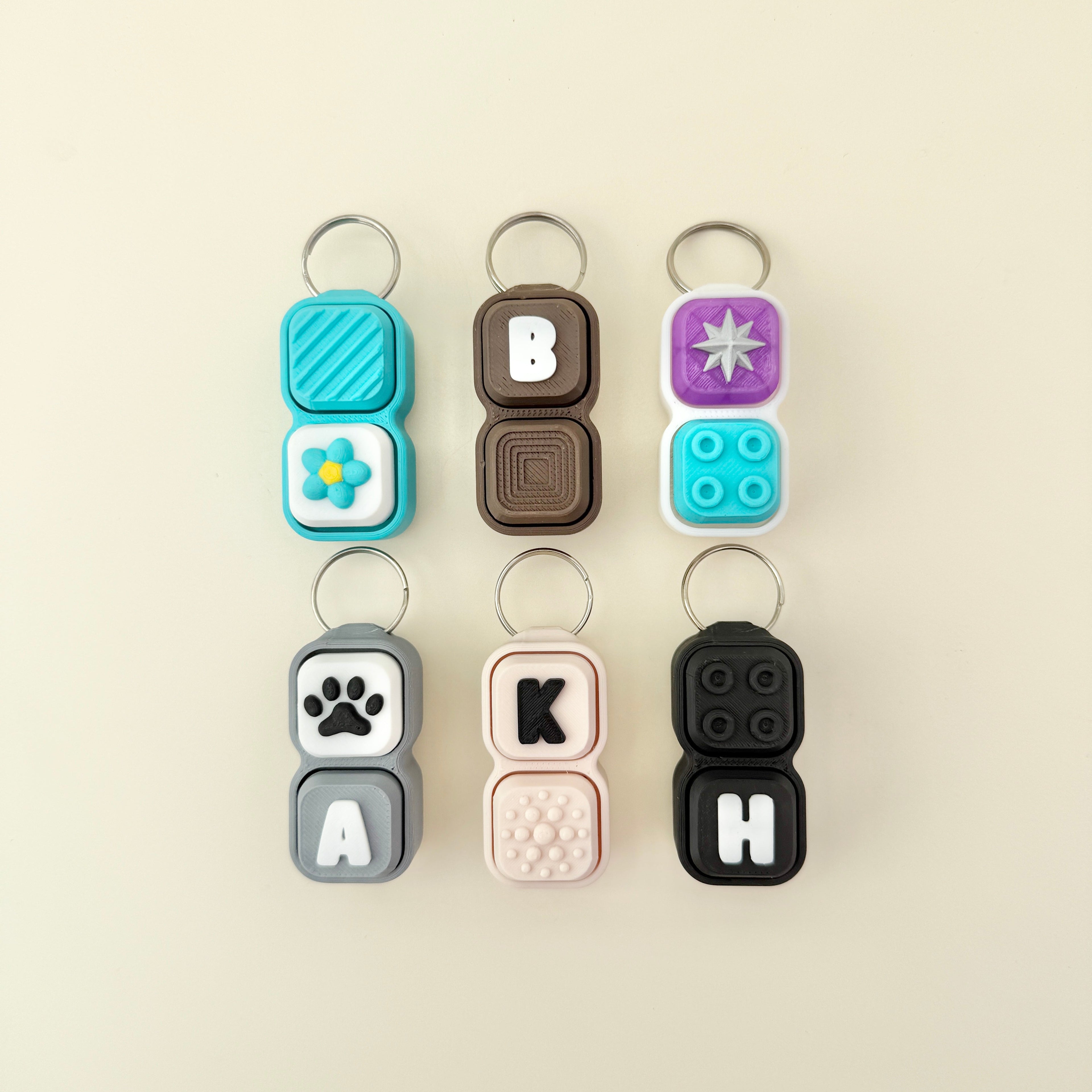 Set of colorful keychains with letter and symbol designs on a beige background