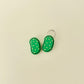 Small green clicker toy with firm top and bumpy surface designed for tactile feedback.