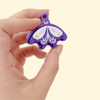 Glitter purple fidget tool with wing shape and gold detailing, designed for tactile input