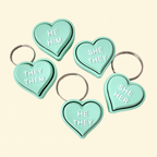 Mint green heart-shaped fidget clicker with “They/Them” pronouns, attached to a keyring.