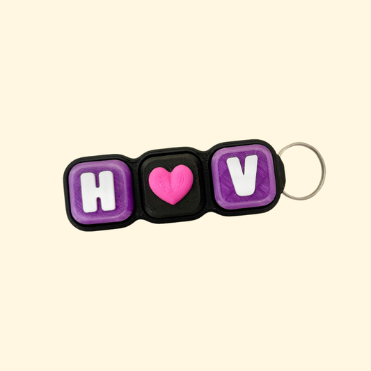 Keychain with 'H', heart, and 'V' letters on a beige background