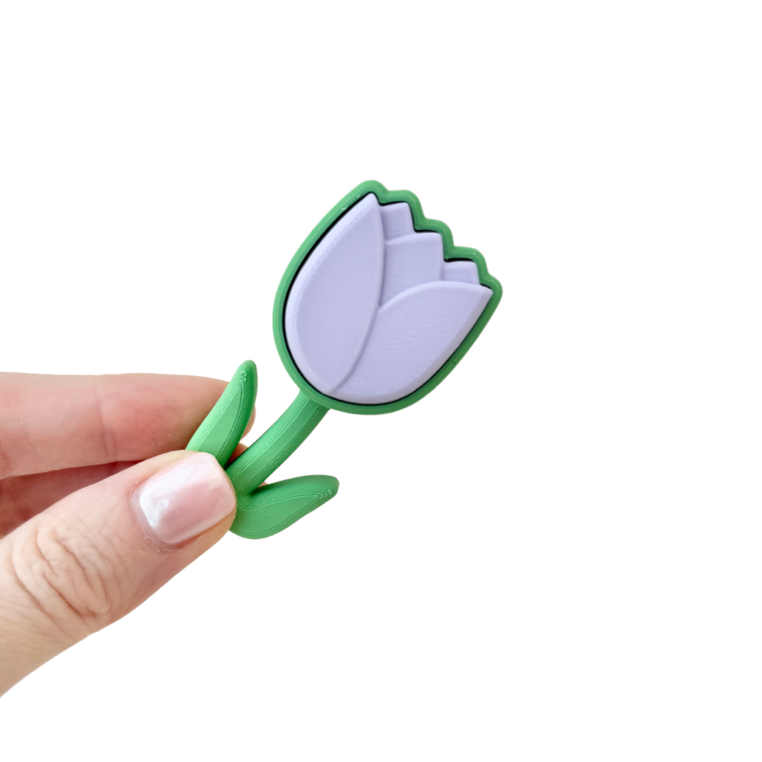 Lilac tulip-shaped fidget clicker toy with a green base, perfect for sensory play and stress relief.