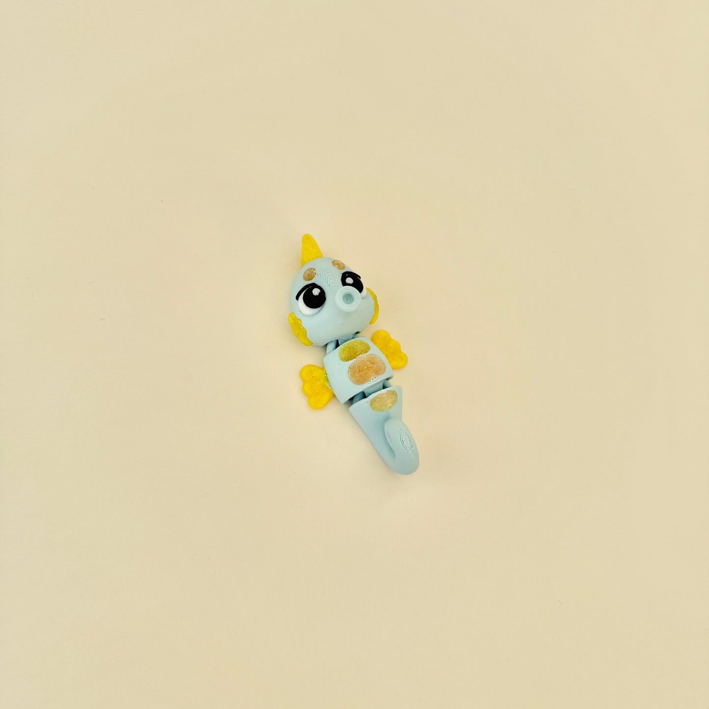 Light blue and glitter yellow fidget in a seahorse shape, designed for sensory use.