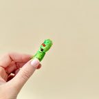 A quirky fidget toy shaped like a pickle, featuring red heart eyes and textured details.