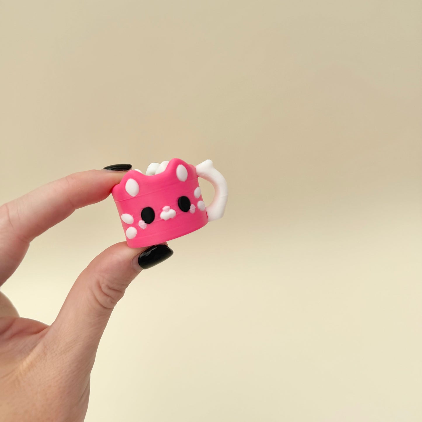 Compact pink mug clicker with raised cat face and pressable marshmallow top.
