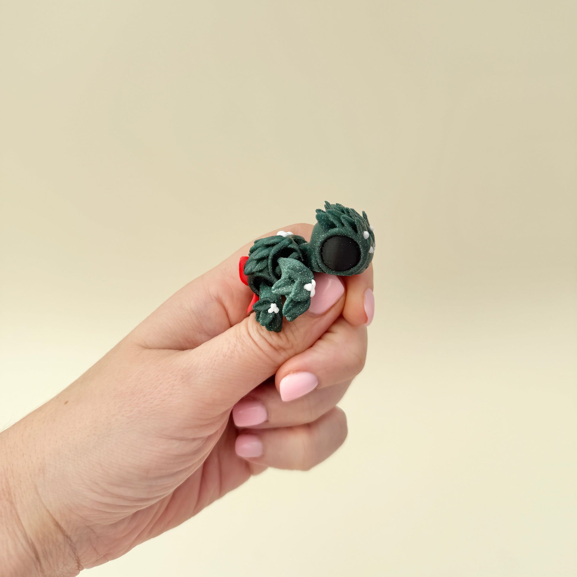 Compact glitter-green turtle with mistletoe-style texture and soft white dot accents for gentle thumb tracing.
