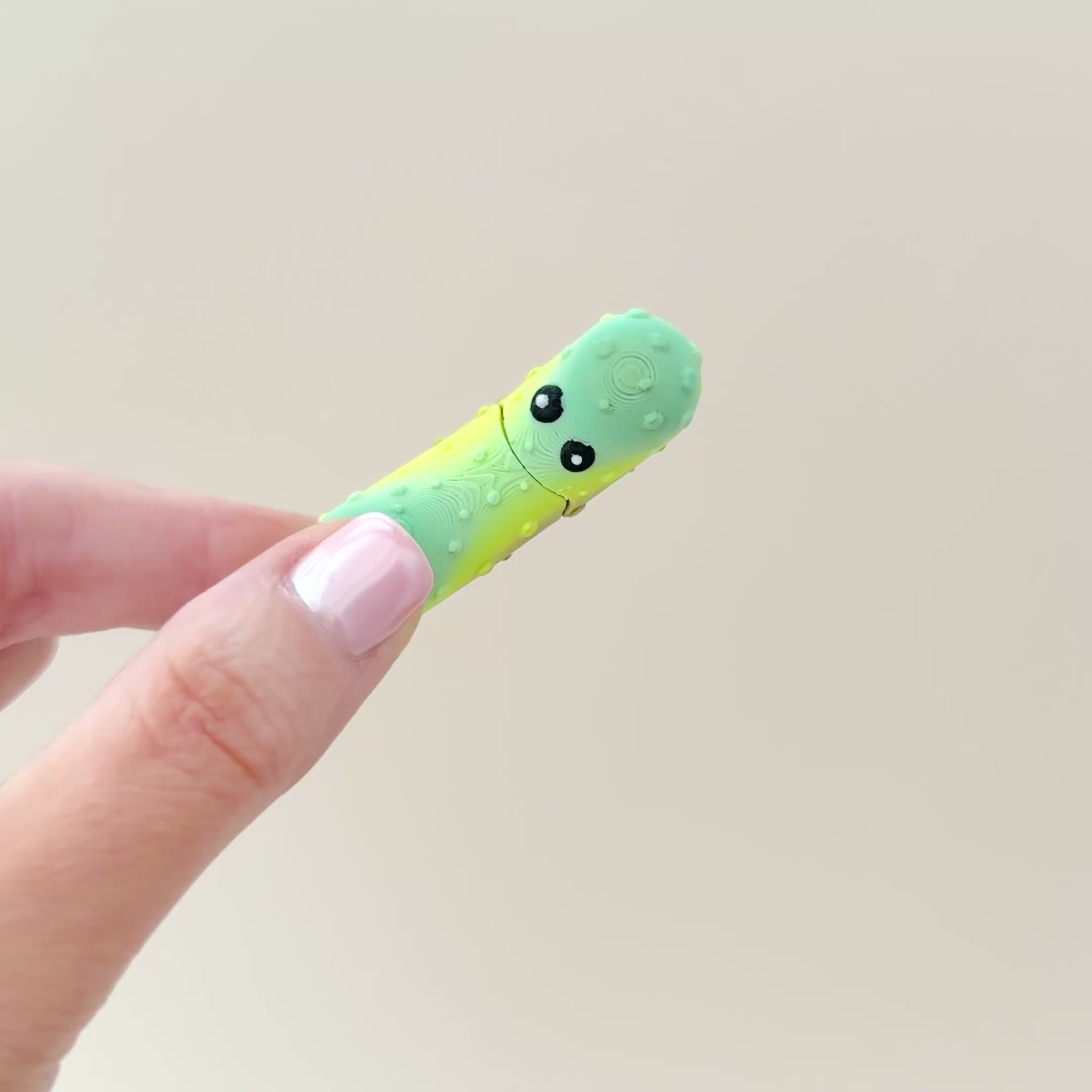 A small pickle fidget toy with realistic textures and a playful interactive mouth feature.
