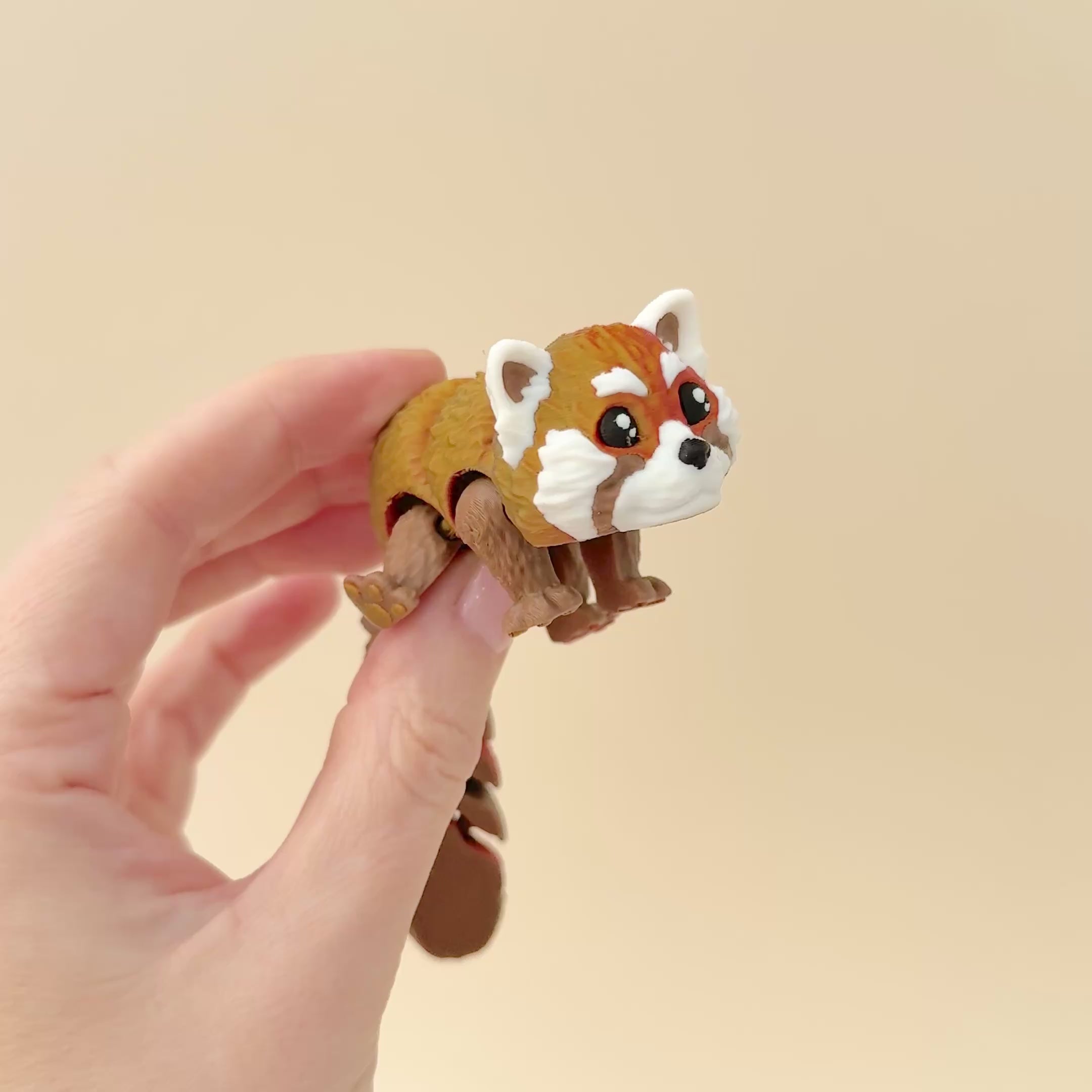 Realistic red panda fidget toy lying flat, showcasing its colour-changing brown and red body with white facial accents.