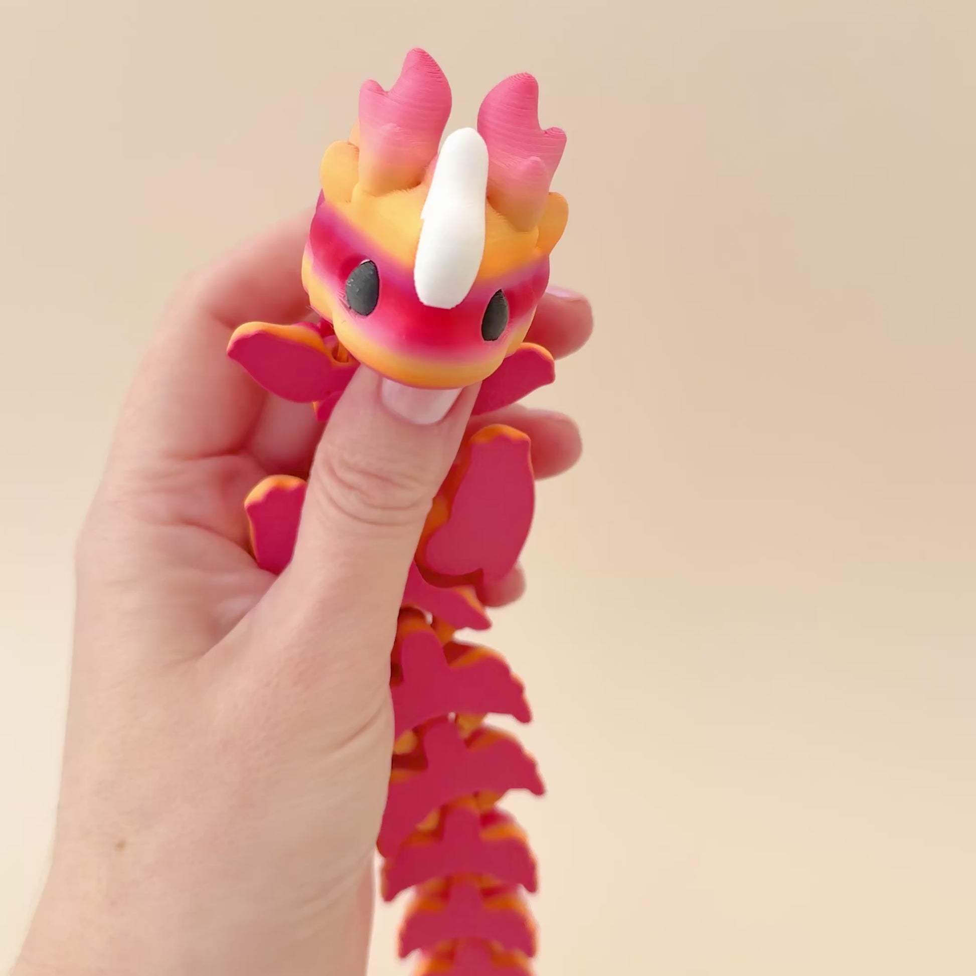 Kaida Scaled Dragon fidget toy in peach and pink tones with white accents and flexible joints.