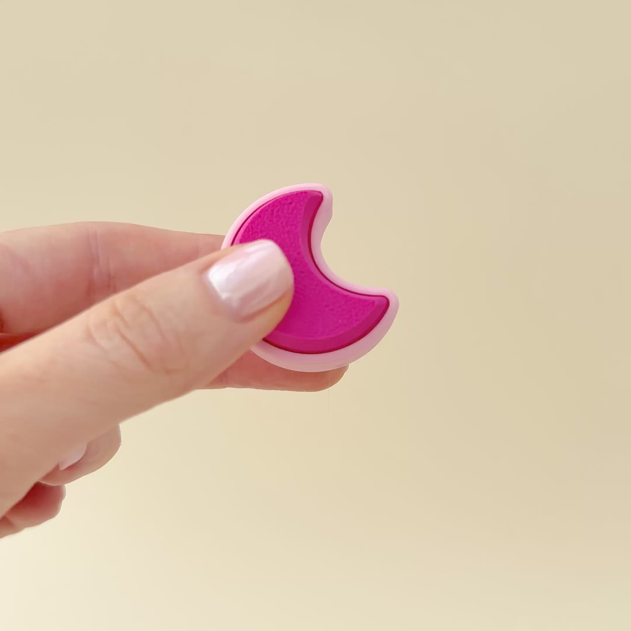 Pastel pink crescent moon clicker for sensory play, stress relief, and portable fun.