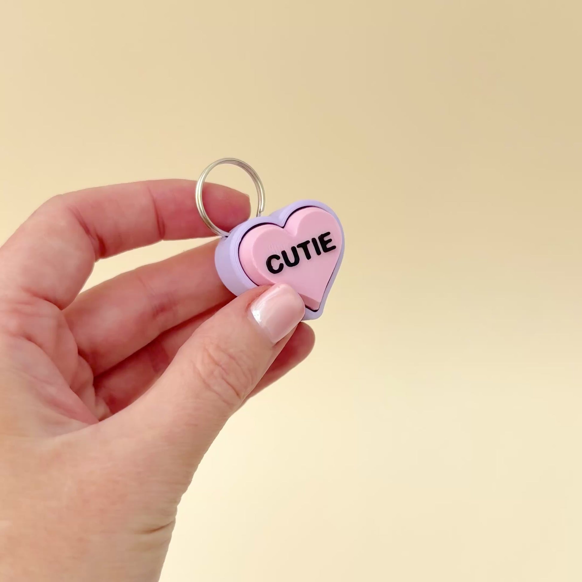 A lilac and pink heart-shaped keyring fidget toy with sweet messages, perfect for gifting.