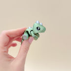 Compact dinosaur fidget toy featuring detailed claws, spikes, and articulated design in two colours.