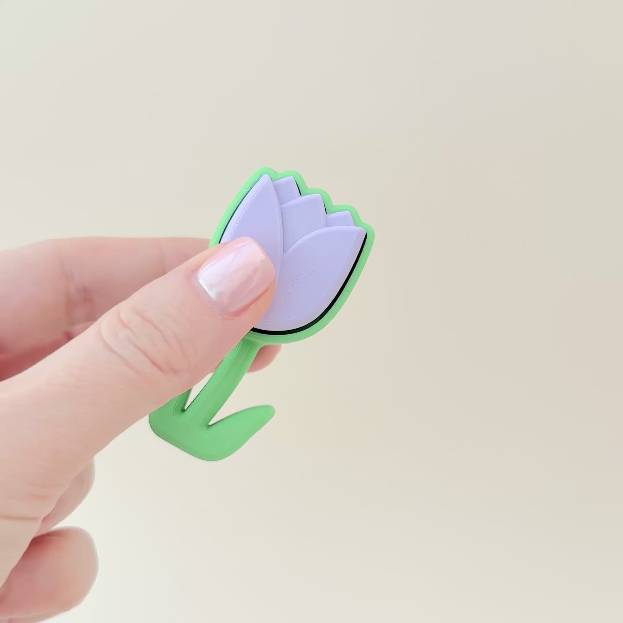 Lilac tulip clicker with a green base, designed for portable sensory play and stress relief.